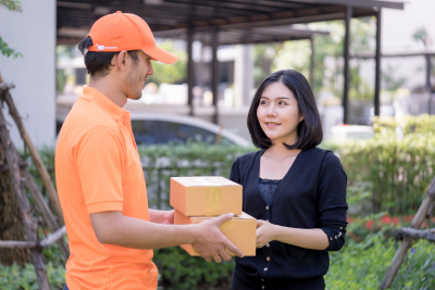 delivery man in orange is handing packages to a woman