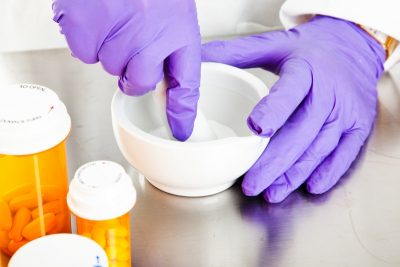 closeup view of a pharmacist's hands using a mortar and pestle